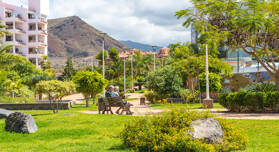 Pareja de ancianos sentada en un banco del parque diseñado por inter jardin en el barranco aquilino en Los Cristianos, Arona