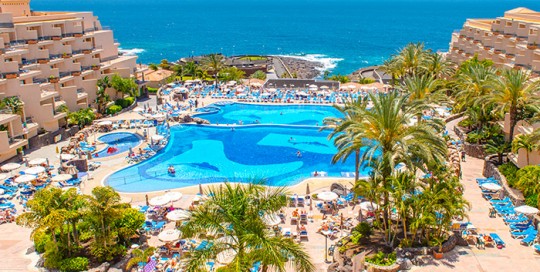 Vista de los jardines, palmeras y la piscina del Hotel Dunas Paraiso Los Cristianos Arona