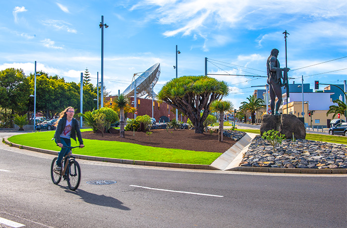 Chico montando en bicicleta junto al paisaje urbano de la rotonda del Museo de la Ciencia y el Cosmos en la Avenida de los Menceyes de San Cristobal de La Laguna